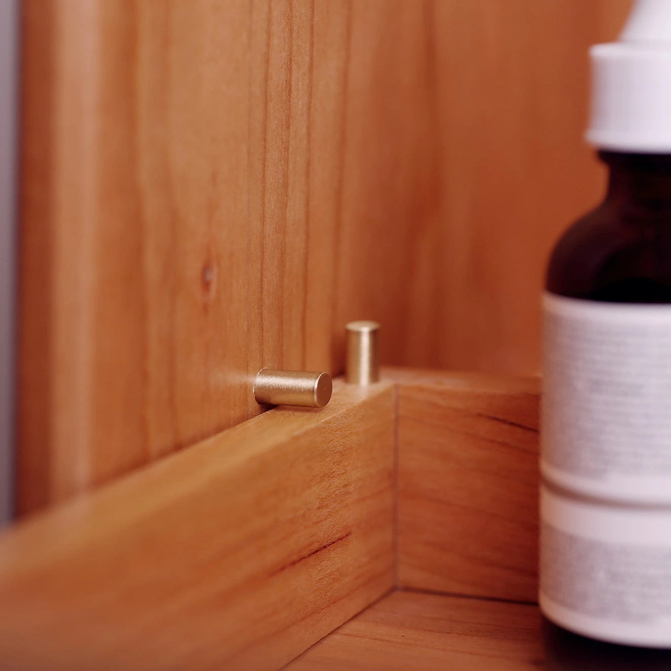 Detail shot of brass drawer-stop pin inside a cherry wood organizer.