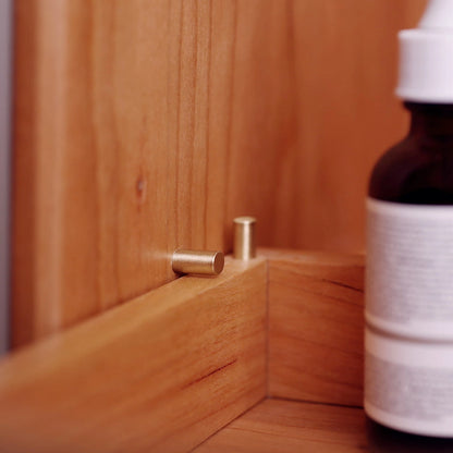 Detail shot of brass drawer-stop pin inside a cherry wood organizer.