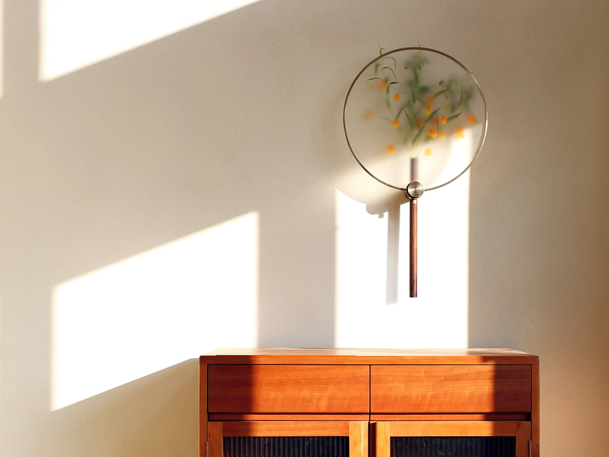 A Japandi wall vase casting dramatic shadows on a wall in sunlight.