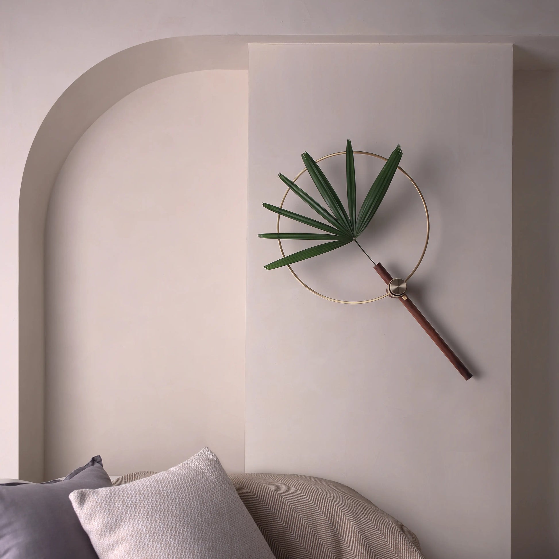 An adjustable wall vase with a fan palm, styled next to an arched wall.