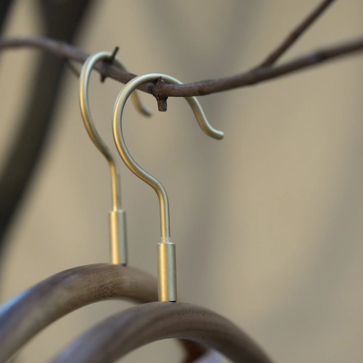Close-up of the brushed brass hooks on two modern wooden hangers.