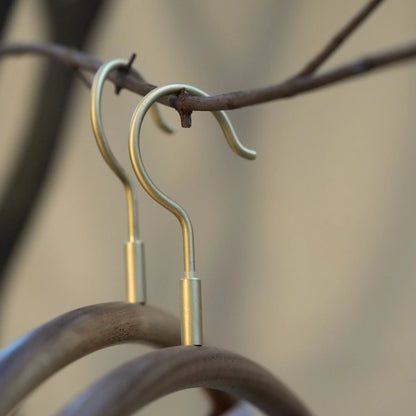 Close-up of the brushed brass hooks on two modern wooden hangers.