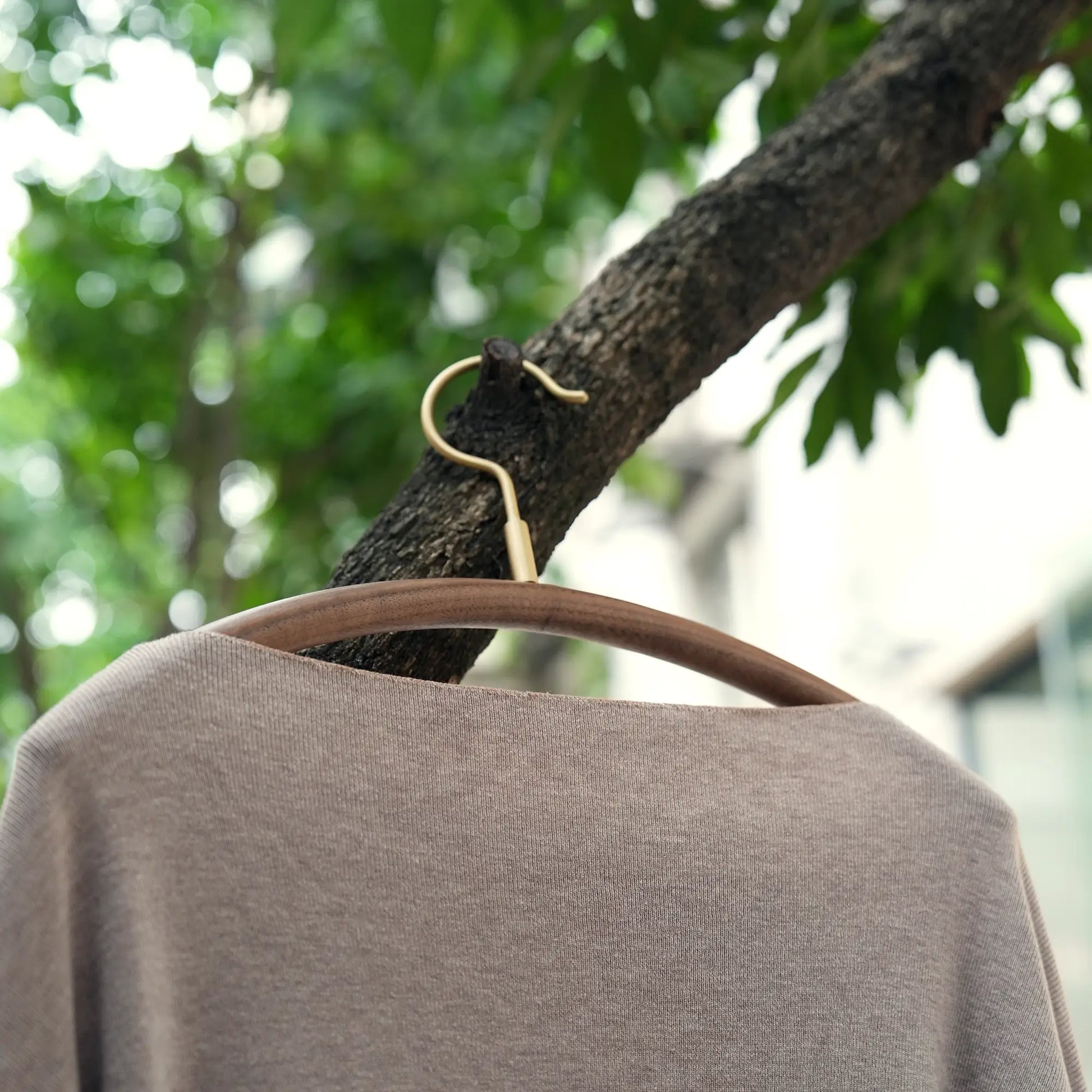 A luxury wooden hanger with a sweater hanging from a tree branch.