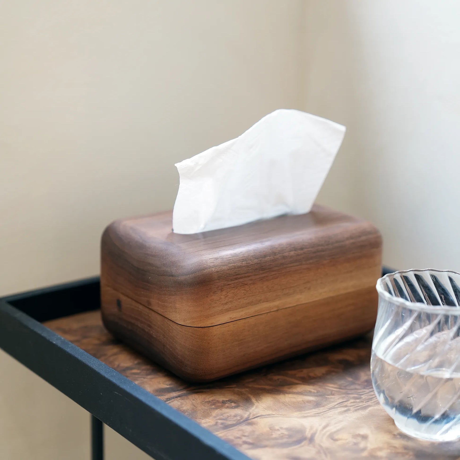 A solid walnut tissue box cover styled on a modern burl wood side table.