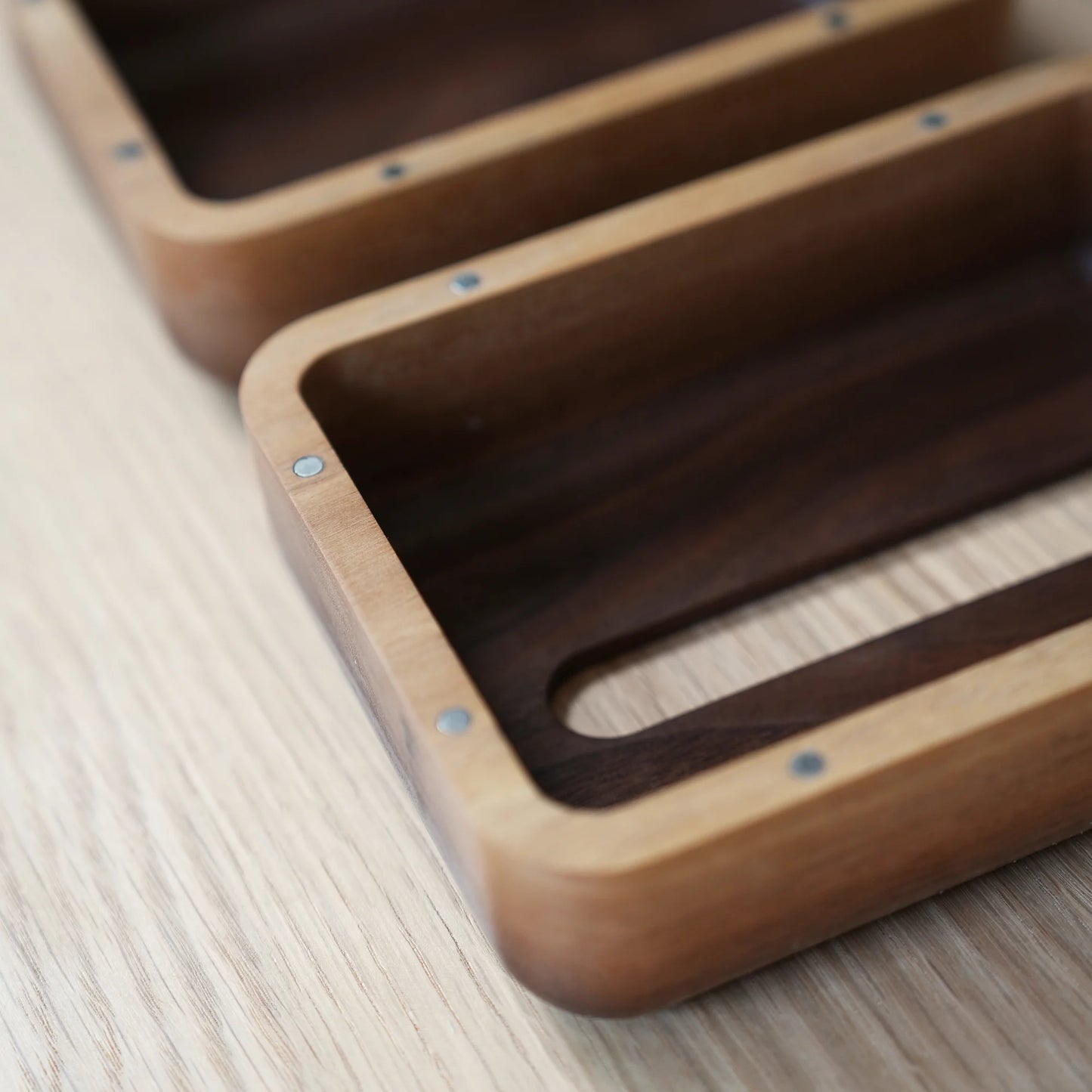 Close-up of the magnetic closure and rounded corners on two walnut tissue boxes.