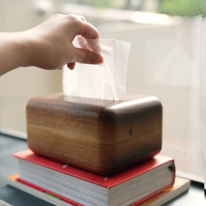 Hand pulling a fresh tissue from the minimalist walnut tissue box cover.