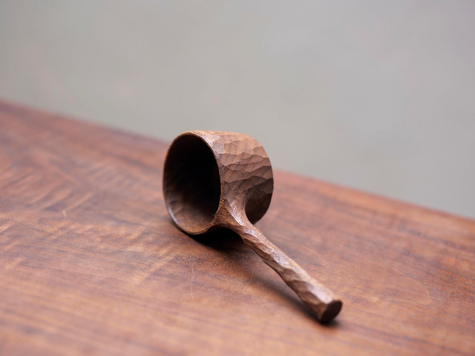 Full view of the wabi-sabi style wooden coffee scoop on a table.
