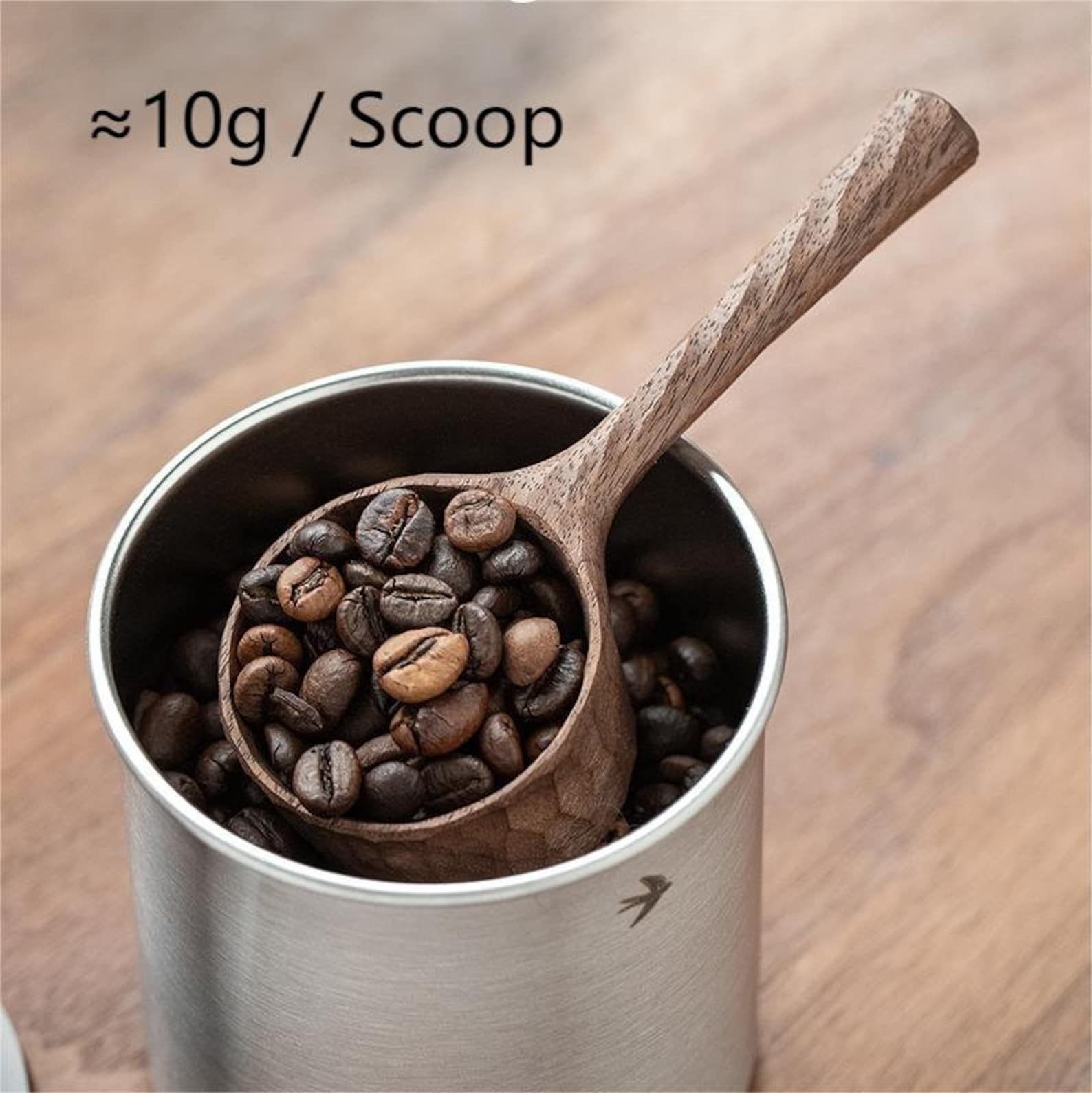 A walnut coffee scoop holding 10g of beans, resting in a coffee canister.