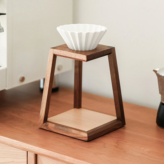 An architectural walnut coffee dripper stand on a light wood kitchen counter.