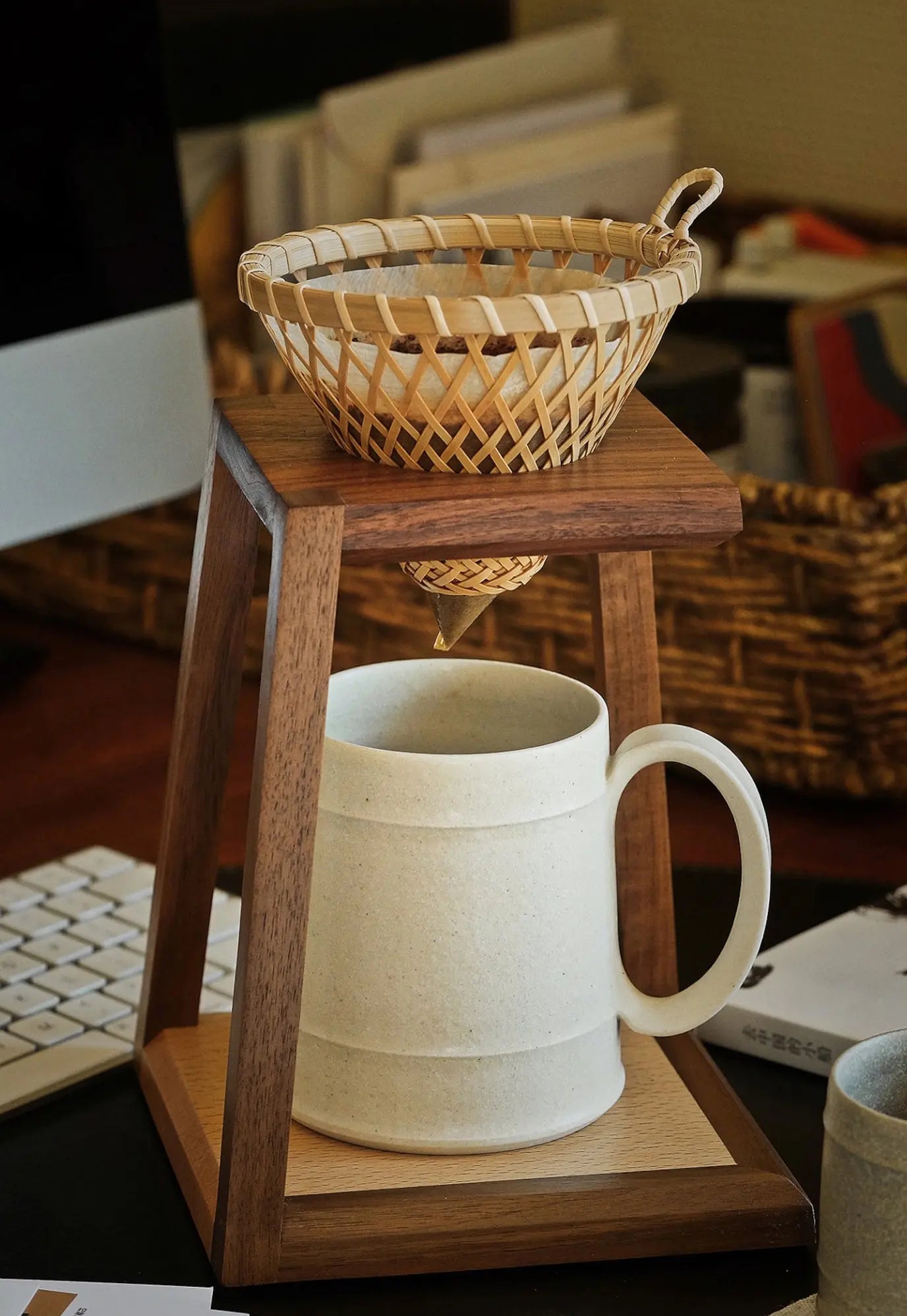 Close-up of a woven coffee dripper on the walnut pour-over stand.