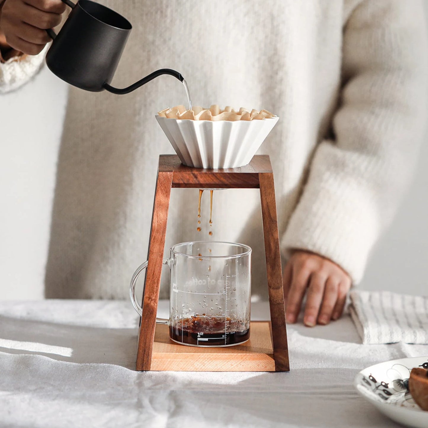 Coffee dripping into a glass mug from a pour-over stand in bright light.