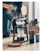 A complete coffee station with a walnut dripper stand and a coffee grinder.