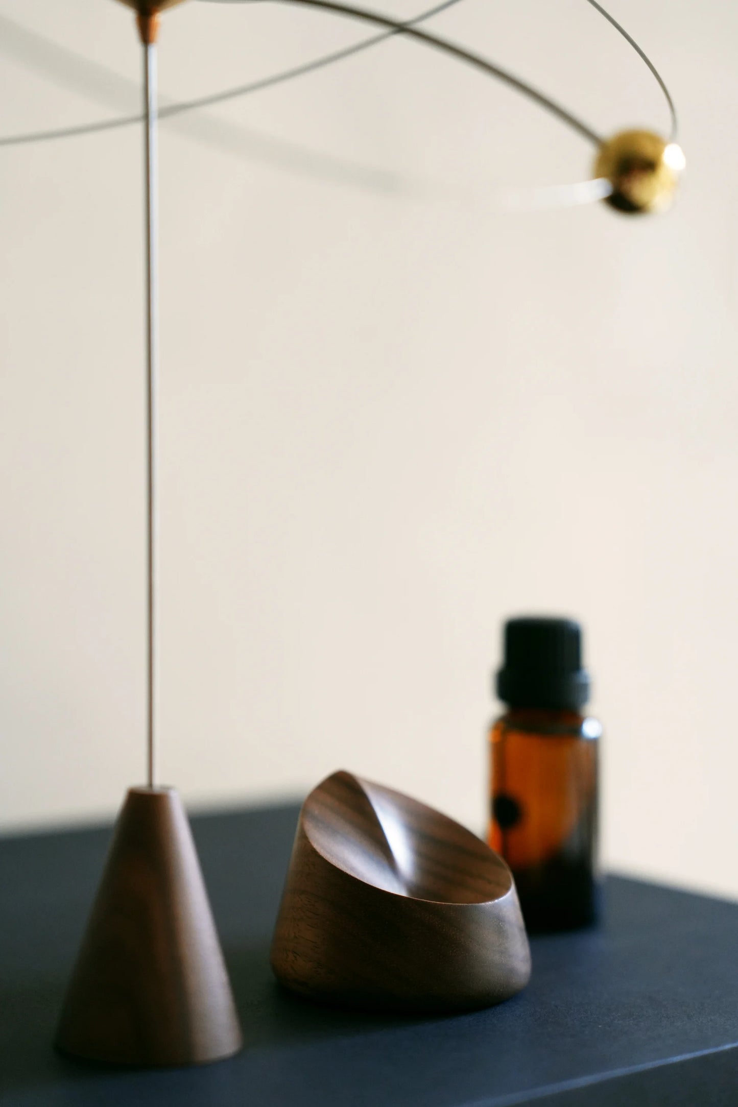 A personal scent diffuser made of dark wood on a modern black desk.