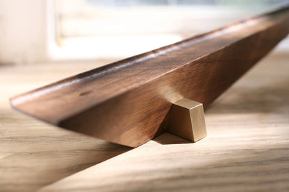 Sunlight catching the edge of a modern, geometric walnut and brass incense holder.