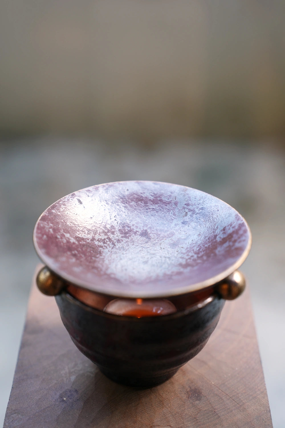 Dark ceramic oil burner with mauve dish, angled view, table decor