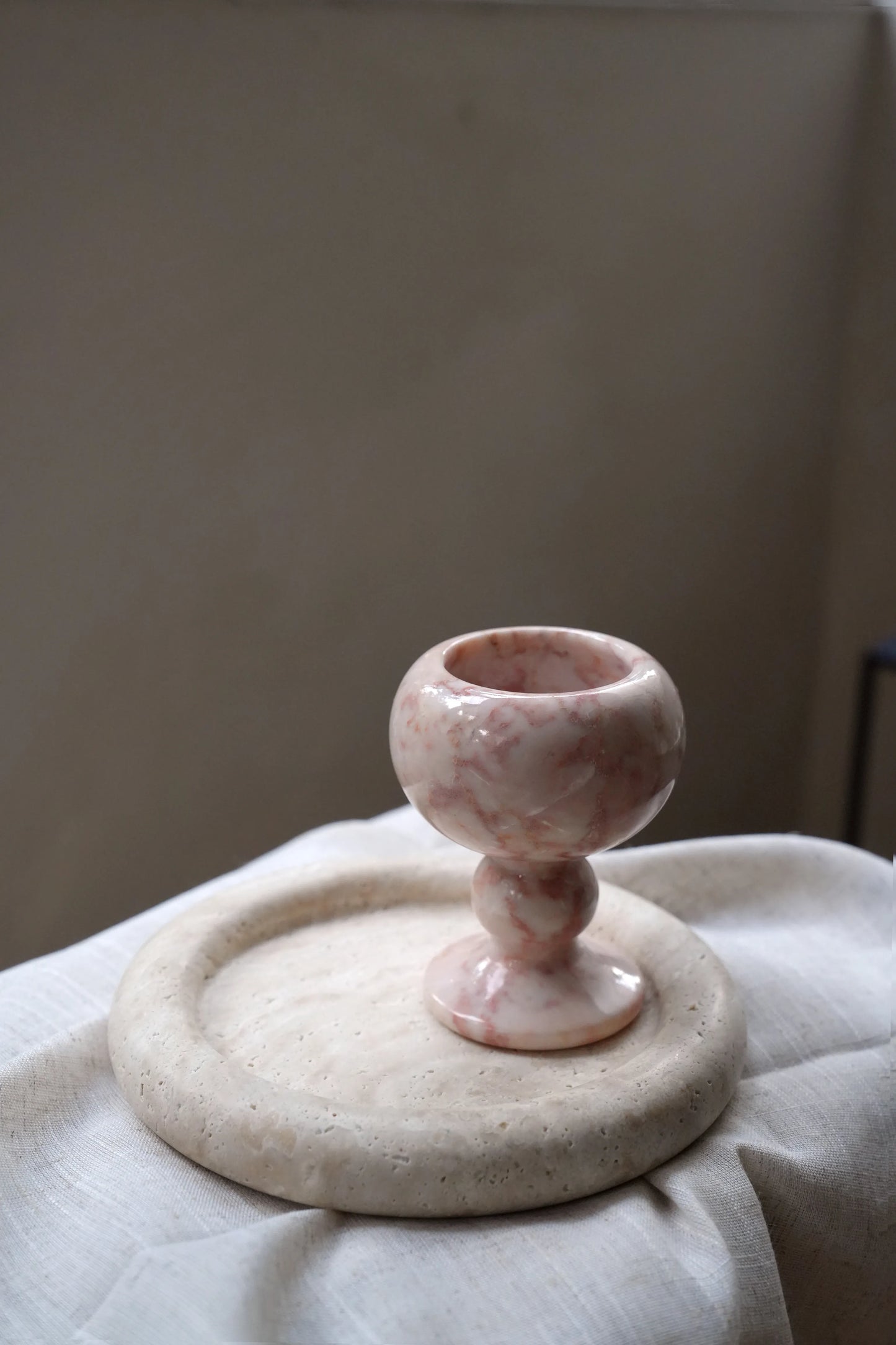 An empty, beautifully veined pink marble goblet on a linen cloth.