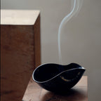 Plume of smoke rising from an organic, dark ceramic ritual bowl.