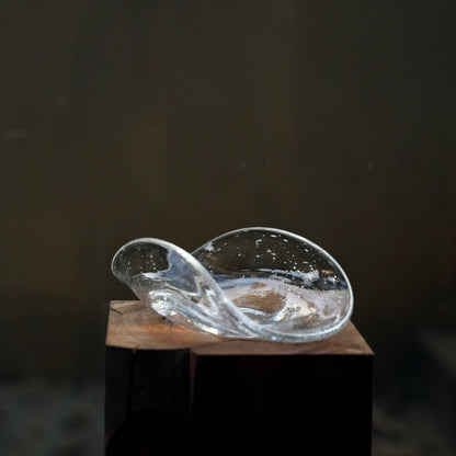 An empty, free-form bubble glass dish sitting on a wooden block.