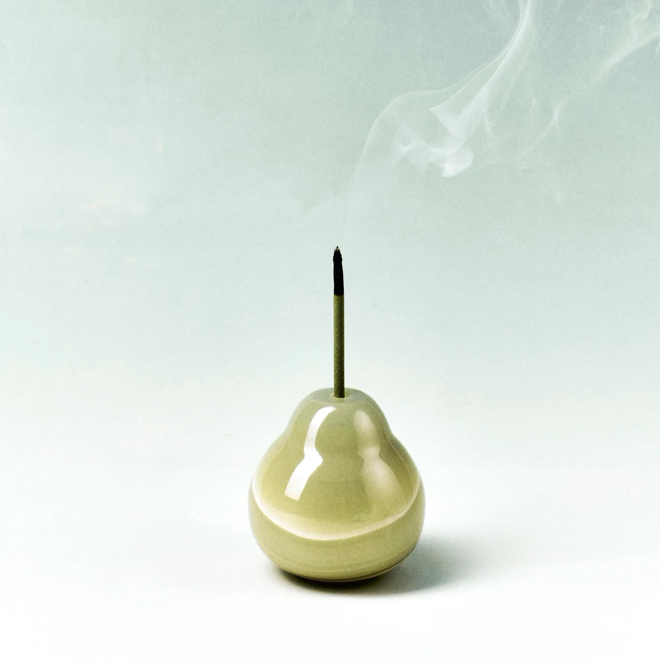 A green ceramic pear-shaped incense holder with smoke rising.
