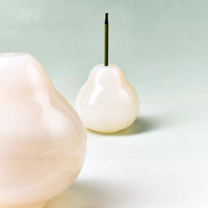 A smooth, light-colored onyx pear decor object next to a larger one.