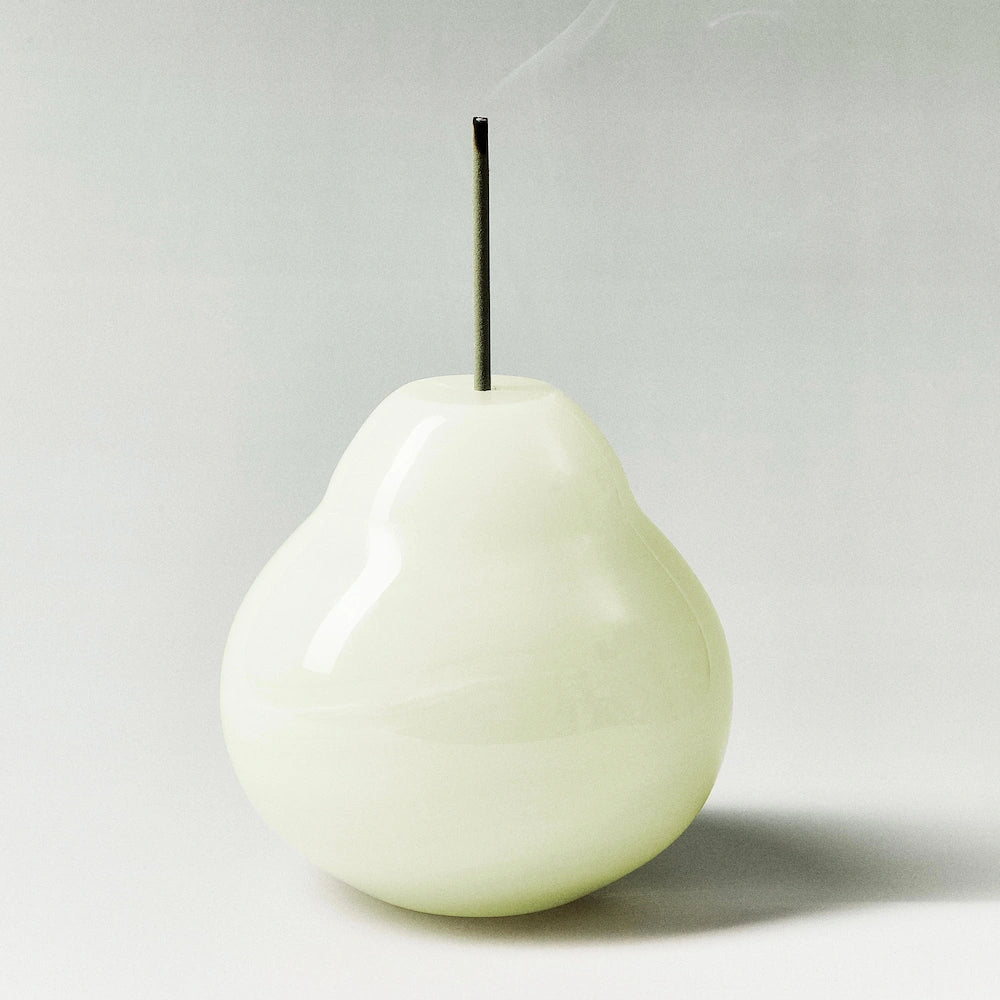 A minimalist white onyx pear incense holder with a green incense stick.