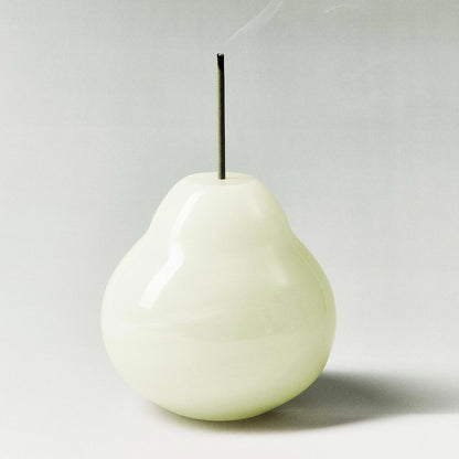 A minimalist white onyx pear incense holder with a green incense stick.