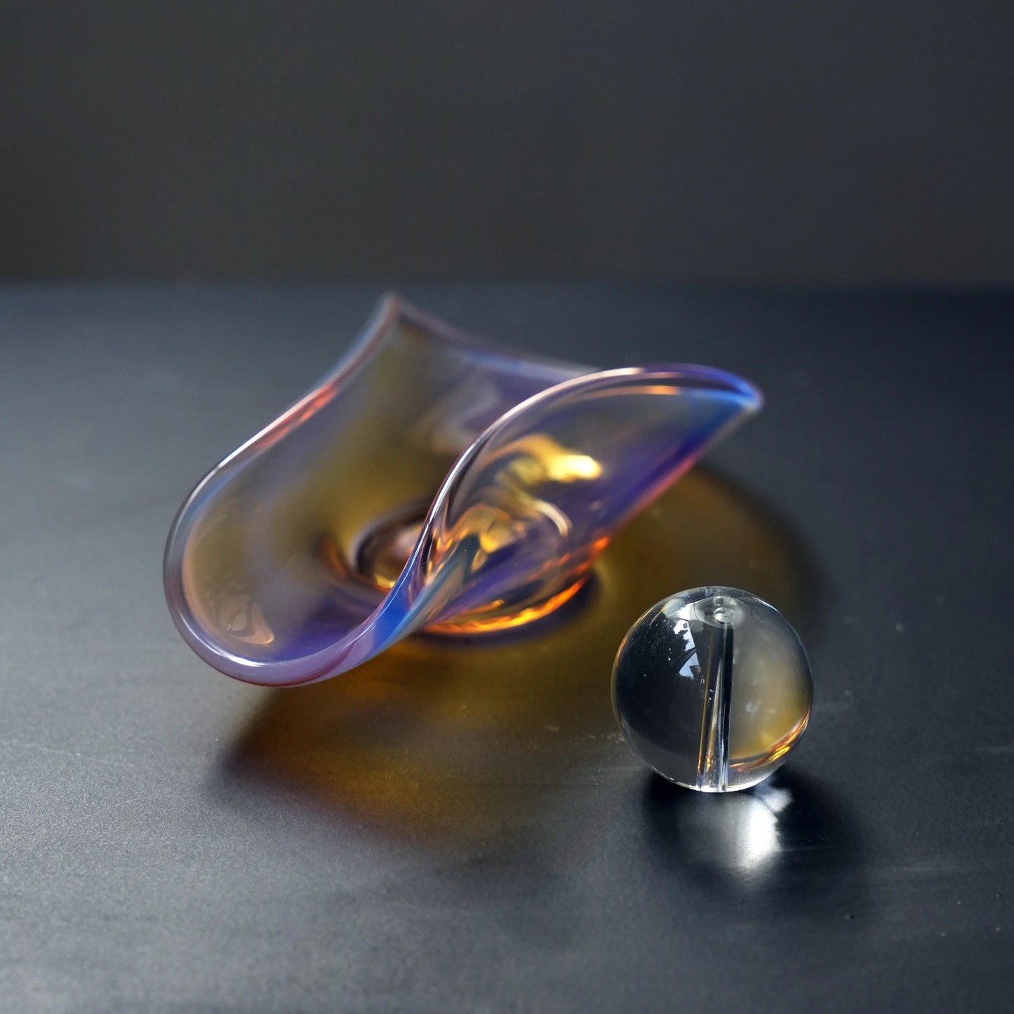 An iridescent glass incense dish and a separate glass sphere holder.