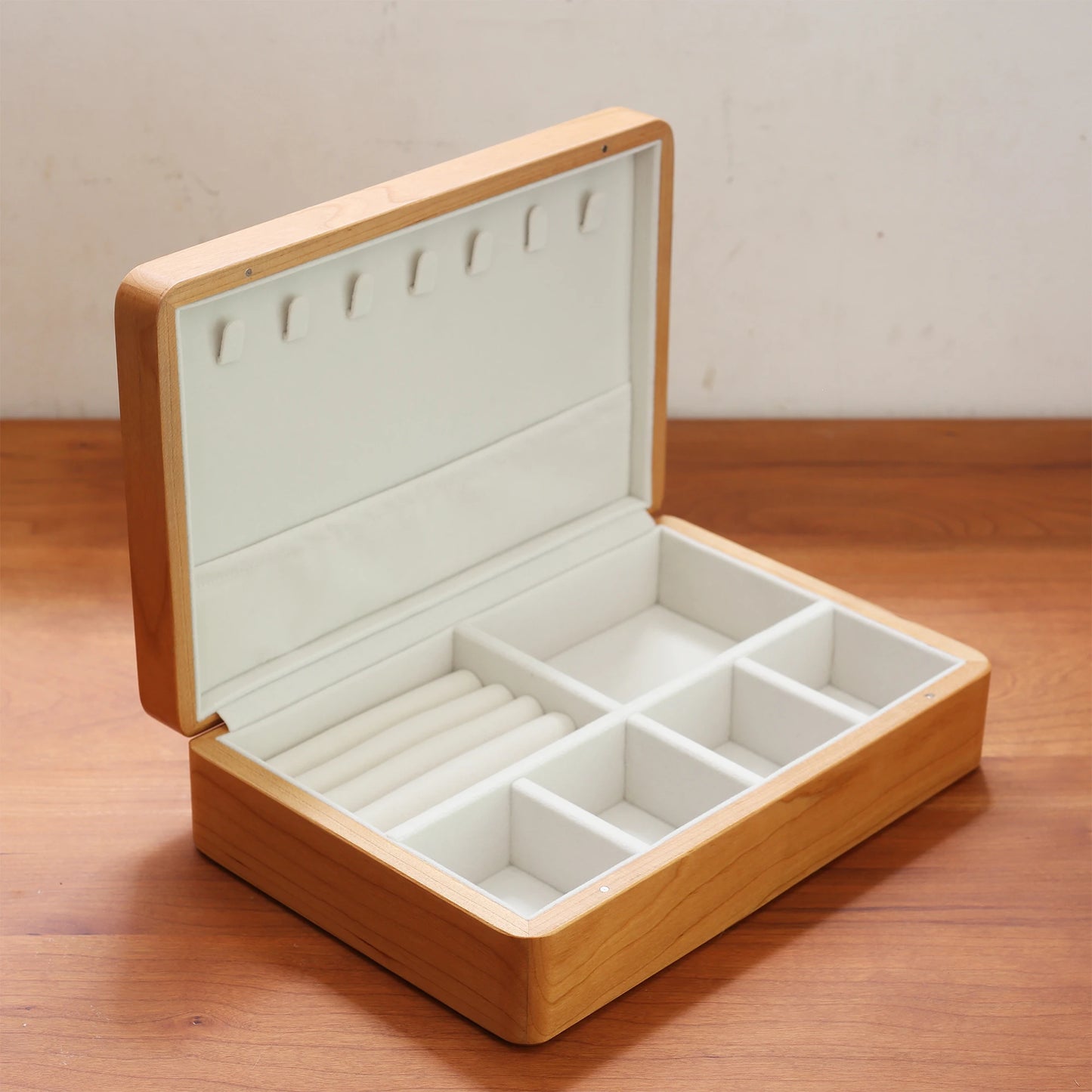 Open cherry wood jewelry box showing soft white interior layout.