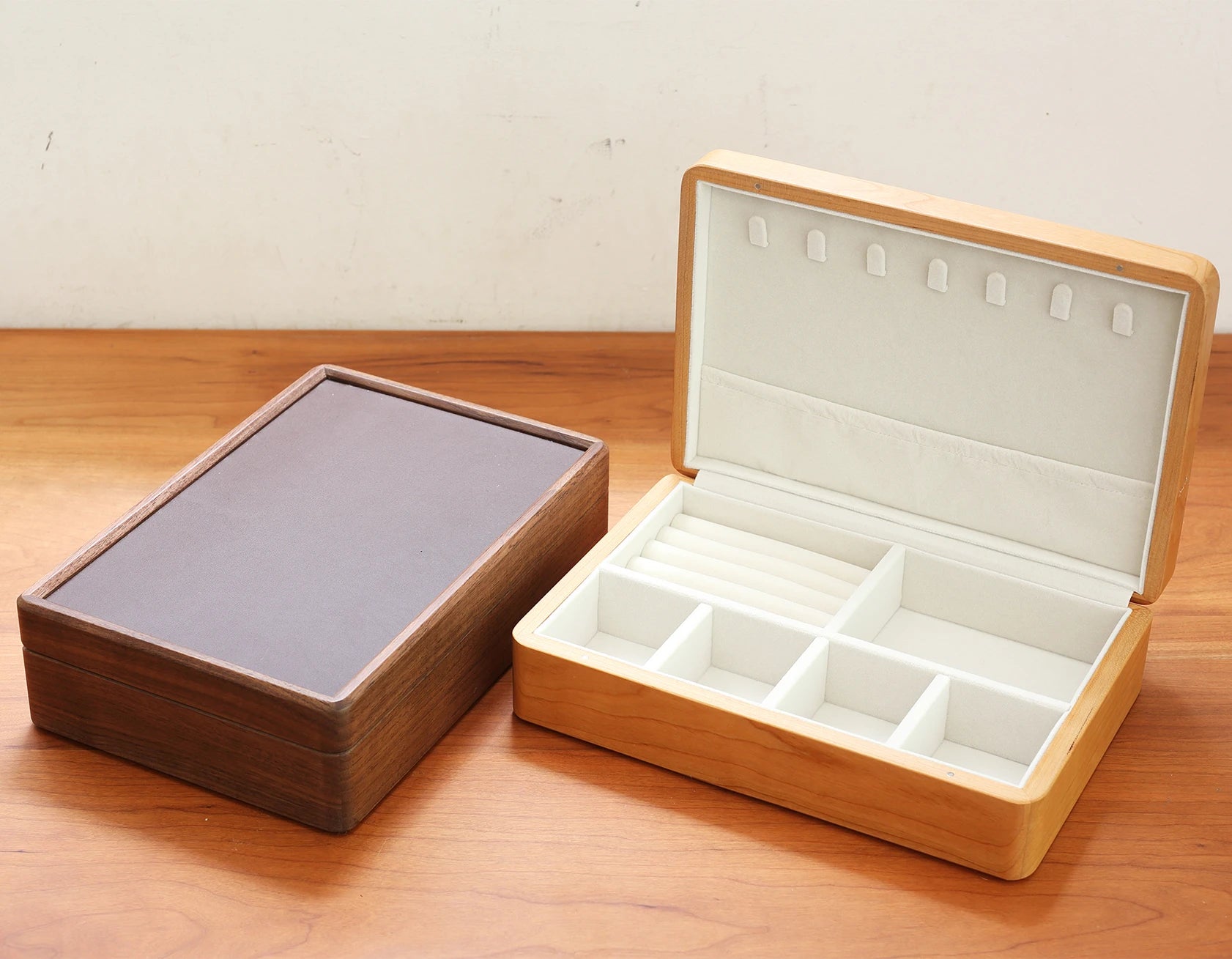 Walnut jewelry box closed next to an open cherry wood jewelry box.