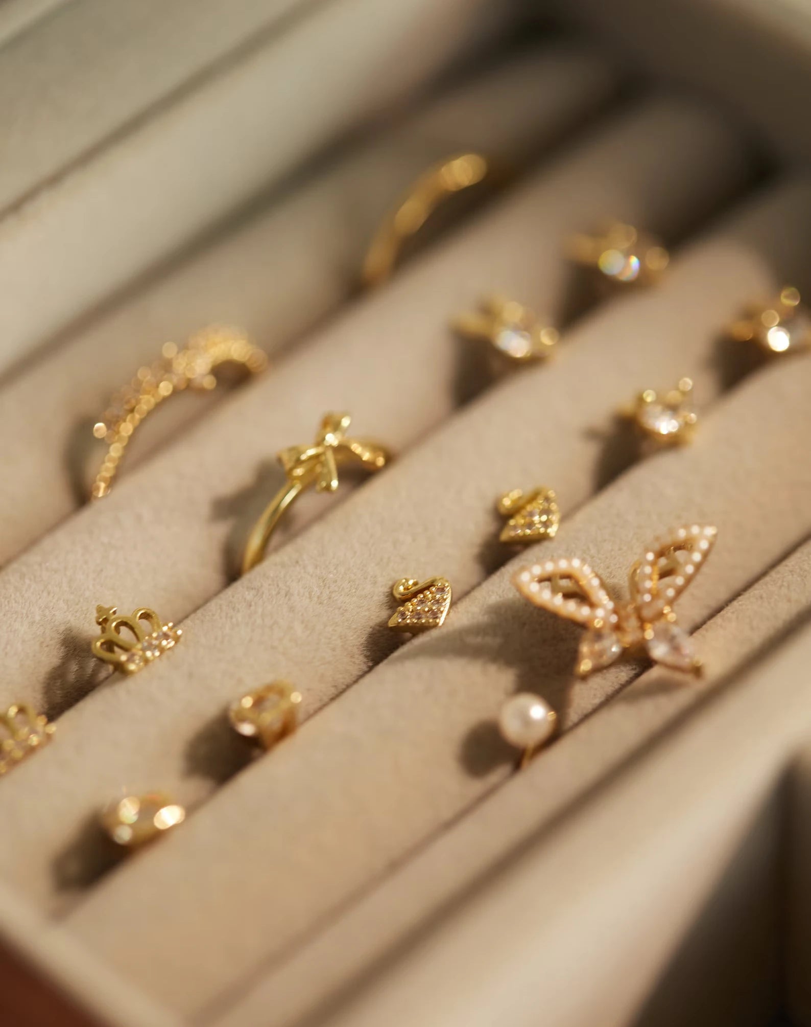 Gold stud earrings organized in the soft ring rolls of a jewelry box.