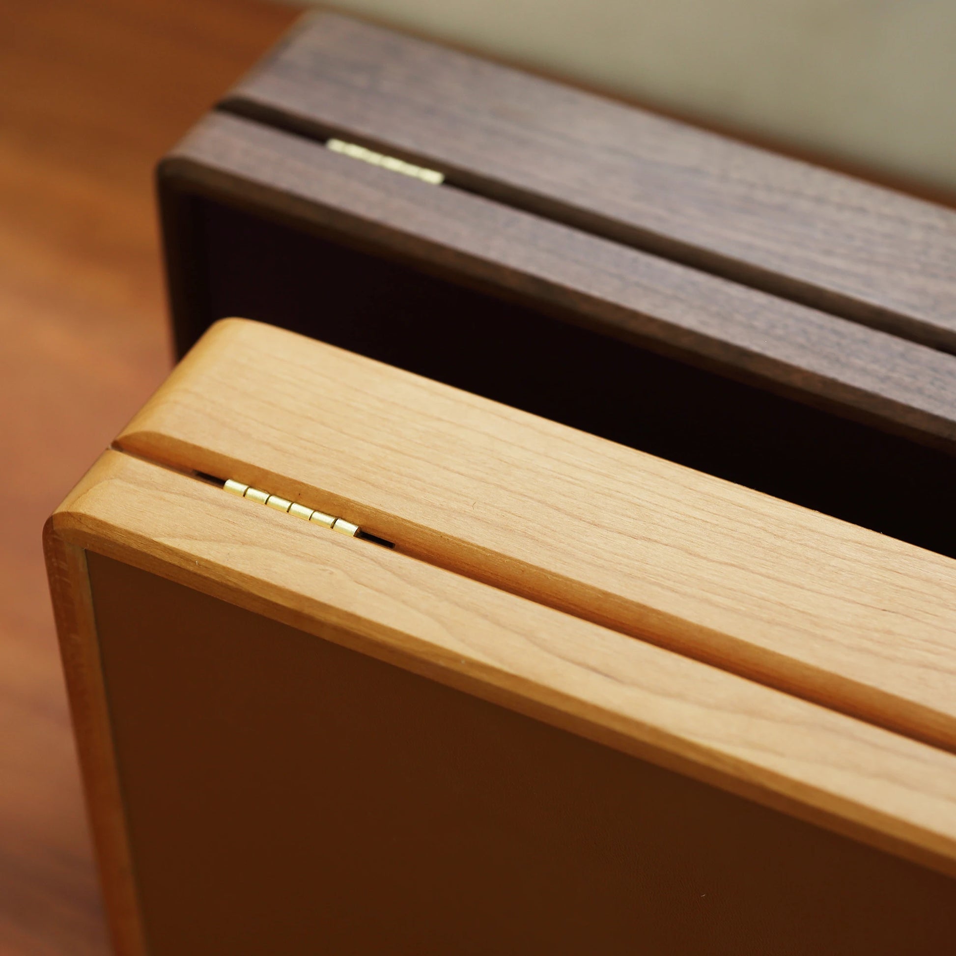 Close-up of brass hinges on walnut and cherry wood jewelry boxes.