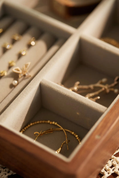Gold hoop earrings and jewelry in a soft-lined box compartment.