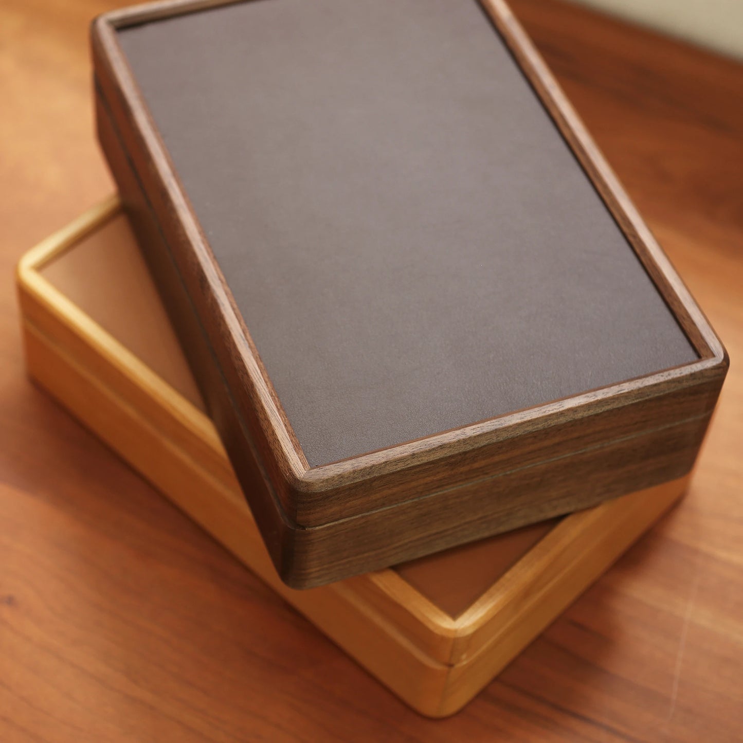 Angled top view of stacked cherry and walnut wood jewelry boxes.