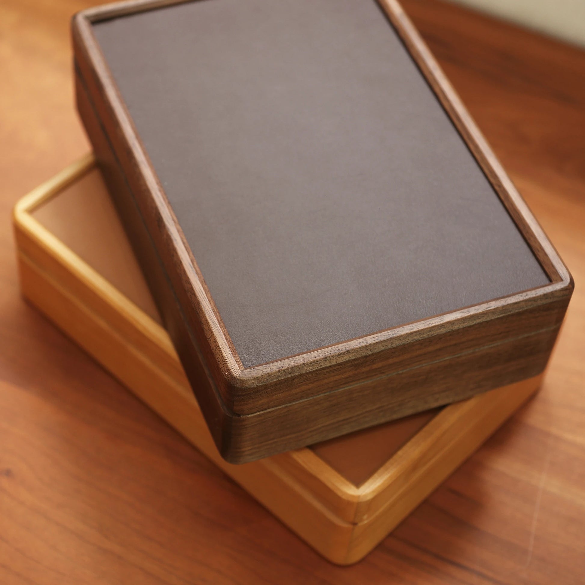 Angled top view of stacked cherry and walnut wood jewelry boxes.