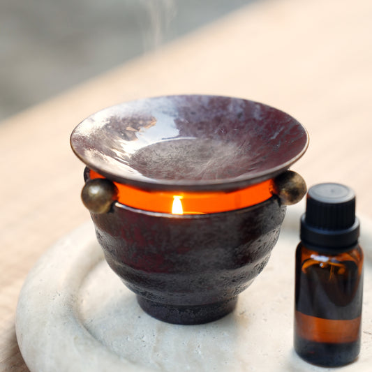 Lit ceramic oil burner with rising steam and essential oil bottle
