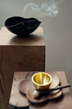 A wabi-sabi ceramic bowl styled next to a small brass singing bowl.