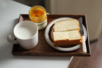 Walnut breakfast tray with bread, jam, and white mug, natural light