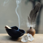  A ceramic ritual bowl styled with a Palo Santo stick and quartz crystals.