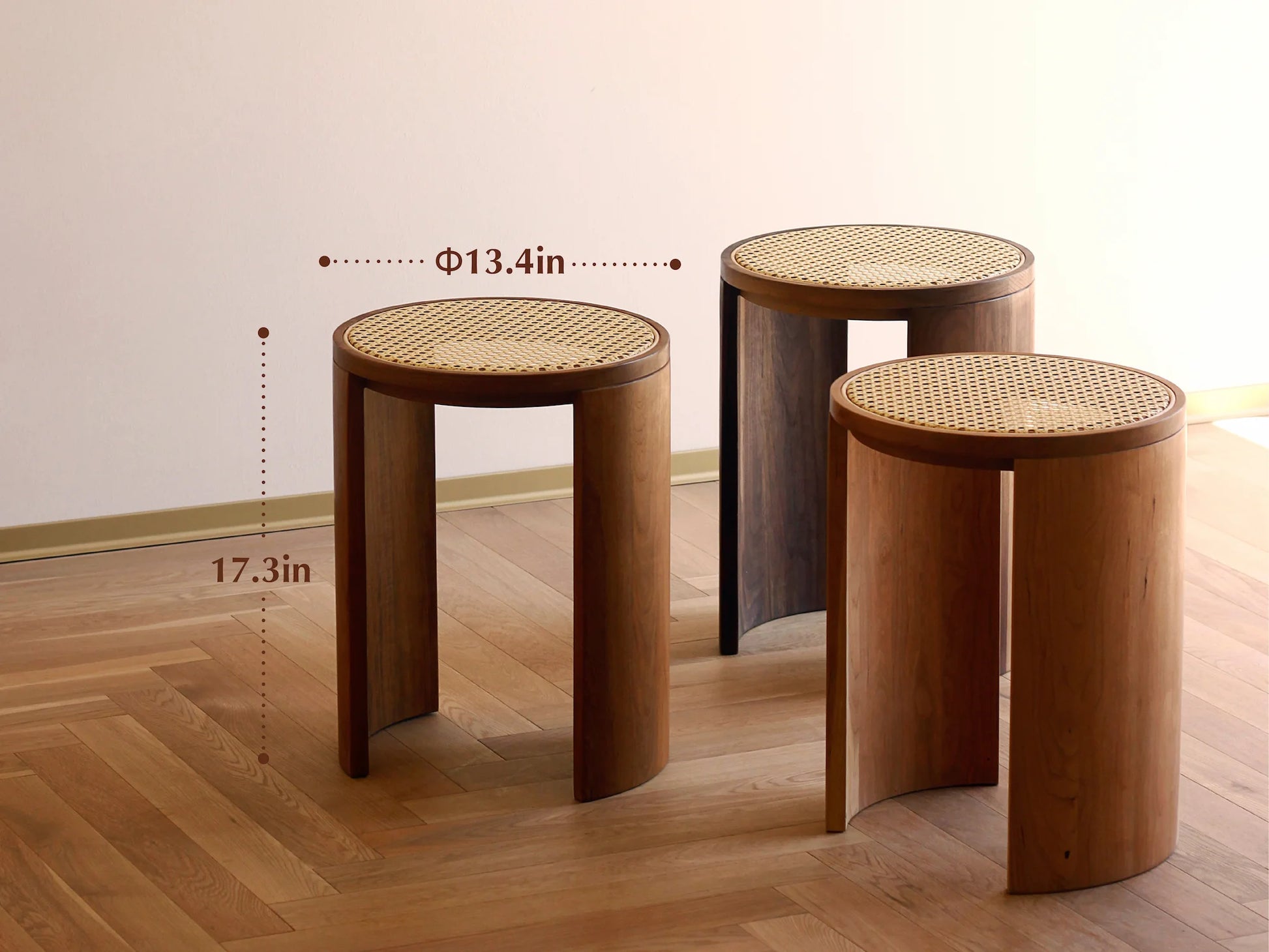 Three rattan stools in different wood finishes: teak, cherry, and walnut.