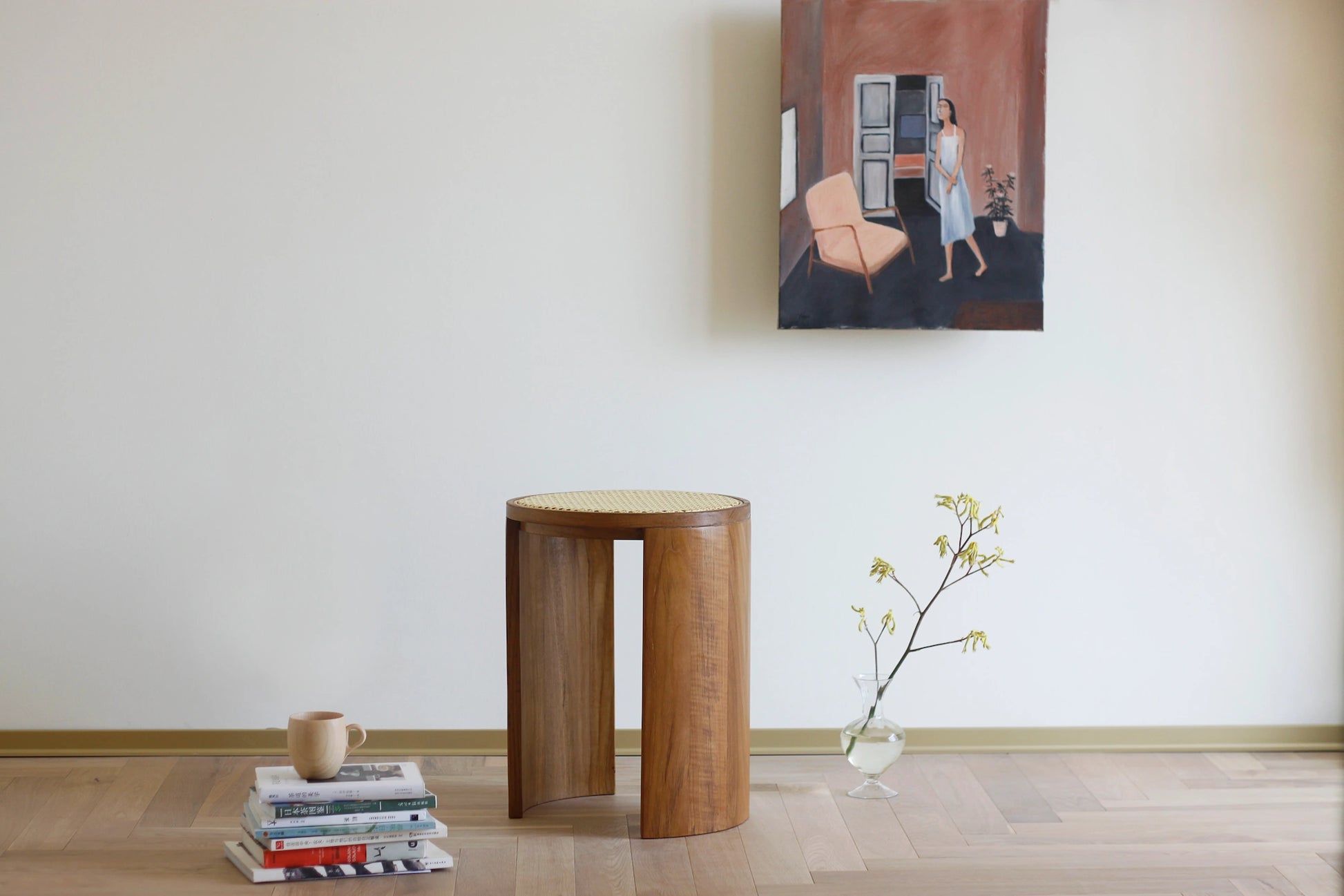 A teak and rattan stool styled as a decorative accent in a minimalist room.