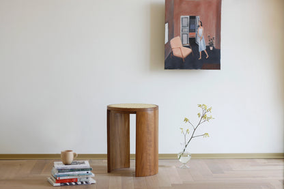A teak and rattan stool styled as a decorative accent in a minimalist room.