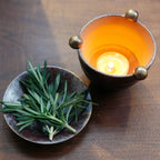 Top-down: ceramic oil burner and dish with rosemary, candle inside